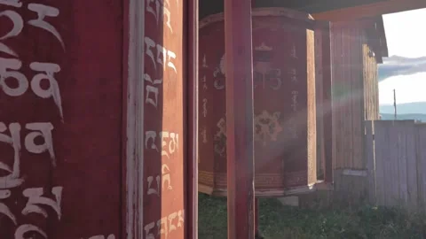 Close-up of huge aged Buddhist prayer wheels slowly spinning at sunset light Stock Footage 223366486