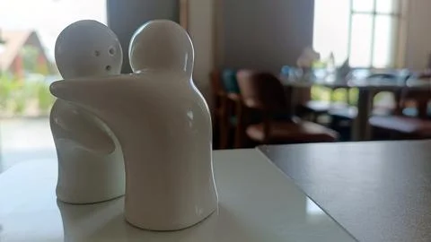 Close-up of hugging ceramic salt and pepper shakers symbolizing love, friendship Foto stock
