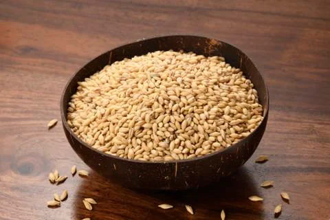 Close up of Hulled Barley in a Coconut Shell Bowl on Wooden Background Stock Photos
