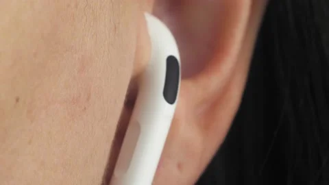 Close-up human ear with a white wireless earphone. A man listens to music with Stock Footage 219920371