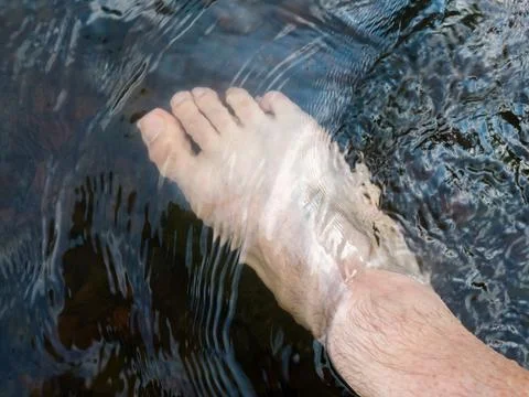 Close up human foot while stand in rapid water stream, relax in shallow creek Stock Photos