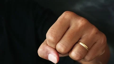A close up of a human hand clenched into a tight fist against a dark background. Stock Footage 344796868