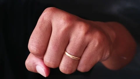 A close up of a human hand clenched into a tight fist against a dark background. Stock Footage 344796878
