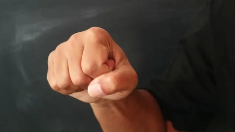 A close up of a human hand clenched into a tight fist against a dark background. Stock Footage 344796935