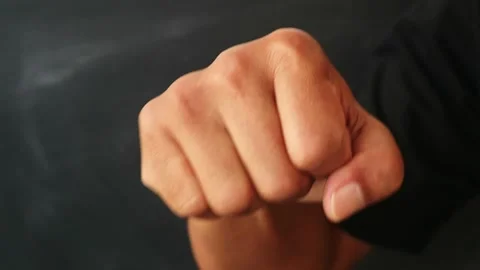 A close up of a human hand clenched into a tight fist against a dark background. Stock Footage 344796974