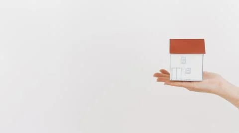 Close up human hand holding mini house model white backdrop. High quality photo Stock Photos