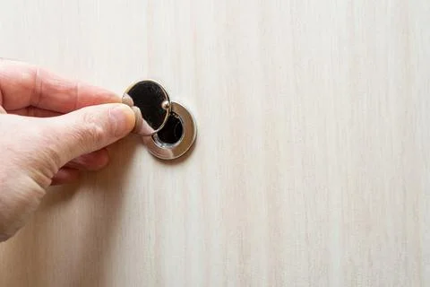 Close up - a human hand opens the peephole cover. Stock Photos