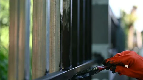 Close up human hand with orange glove holding painting many times on iron fence  Stock Footage 153403222