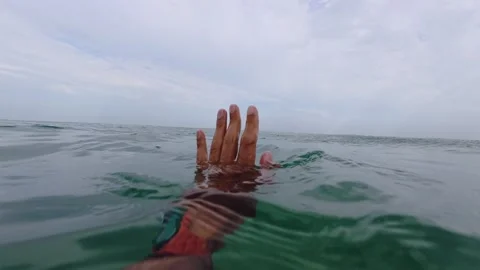 Close-up of a human hand partially submerged in the ocean, reaching out above Stock Footage 317170489