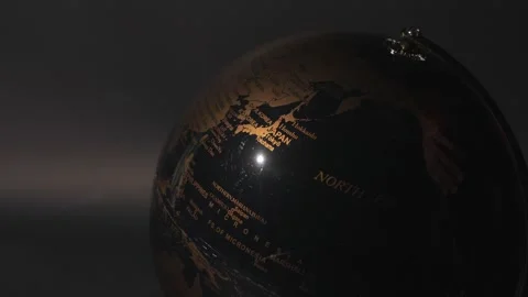 Close up of human hand rotating antique style globe with golden continents on Video stock 314762369