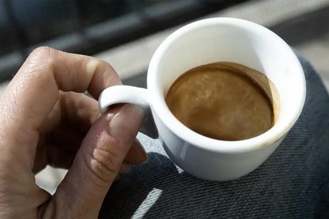 Close up of Human hand with small white empty cup espresso coffee in bright 写真素材