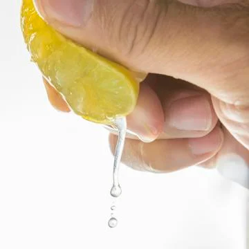Close up Human hand squeezing half of lemon on white background Stock Photos
