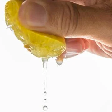 Close up Human hand squeezing half of lemon on white background Stock Photos