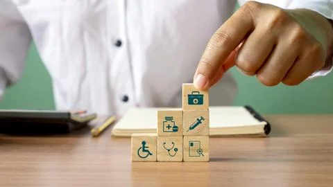 Close-up of human hand stacking wooden blocks overlapping health care icons.. Stock Photos
