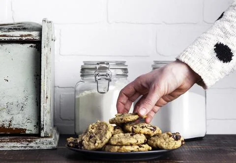 Close up of human hand taking a chocolate chip cookie from the plate. 스톡 사진