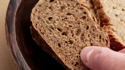 Close up of human hand taking a slice of dark German bread Stock Footage 333621873