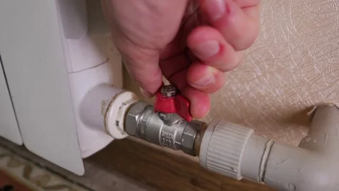 Close Up of Human Hand Turning Red Radiator Valve to Control Home Heating Stock Footage 339212063