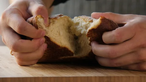 Close-up human hands break a whole freshly baked homemade bread in half 스톡 동영상 168185886