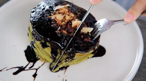 Close up of human hands cutting yummy healthy vegan pancakes with organic black Stock Photos