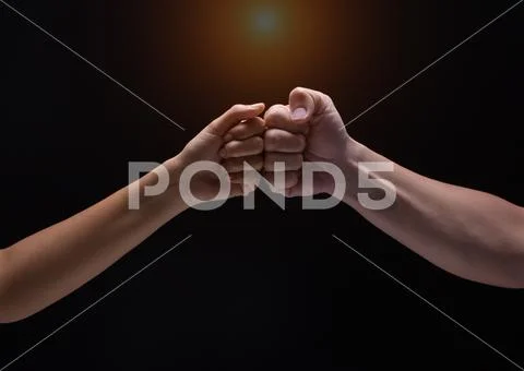 Close up of human hands making a fist bump on black background. a fist pump Stock Photos