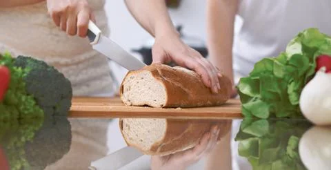 Close-up of human hands slicing bread in a kitchen. Friends having fun while Stockfoto's