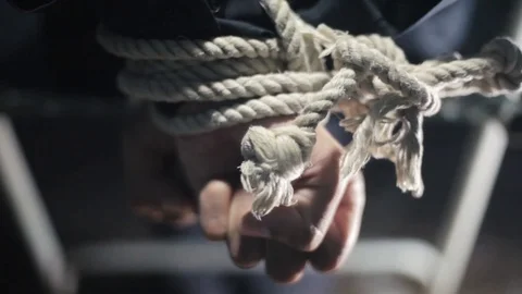 Close up of human hands tied with white colored rope and sitting on a metal. Stock Footage 106698265