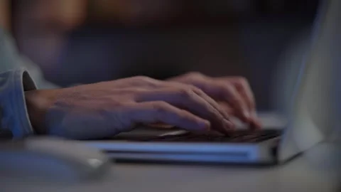 Close up human hands typing on laptop keyboard at night. Unrecognizable white Stock Footage 253860393