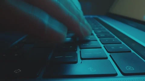 Close up of human hands typing on a laptop computer keyboard in a dimly lit.. Video stock 337519206