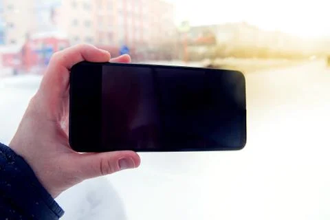 Close up of human hands using smartphone outdoors against cityscape Foto stock