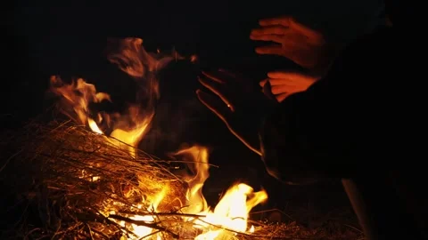 A close-up of human hands warming themselves around a campfire in nature. Stock Footage 321174789