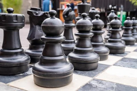 Close up of human sized black chess pieces with pawns in front Foto stock