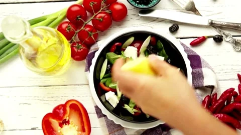 Close-up human Squeezes a Half Cut Lemon over a Salad in Kitchen. Cooking V.. Stock Footage 265840500
