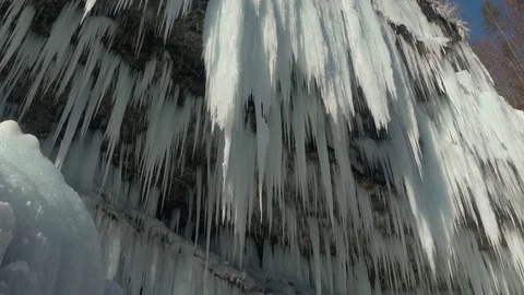 CLOSE UP: Hundreds of sparkling icicles hanging off a mountain cliff in winter Stock Footage