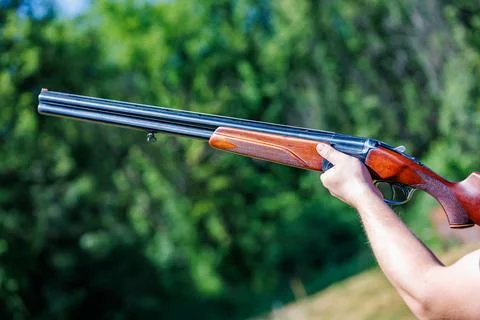 Close-up of hunter hands aiming double-barreled shotgun outdoors, hunting season Stock Photos