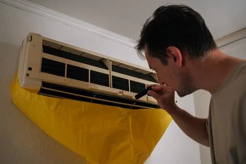Close-up of HVAC technician using flashlight, inspecting air conditioning unit Stock Photos