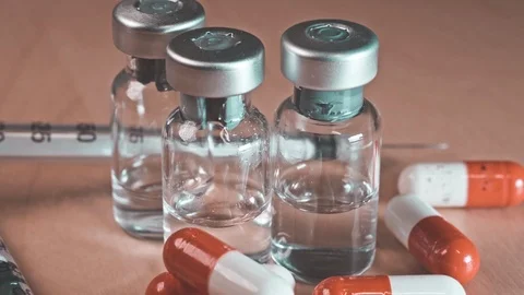 Close up of a hypodermic needle and red pills Stock Footage 117248244