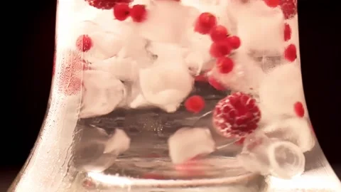 Close up on ice and berries flowing in cool water. Refreshing summer drink with Vídeos de archivo 149898482