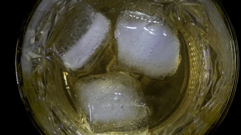 Close-up. A ice cube falls and melts in a glass of whiskey. Stock Footage 124527220