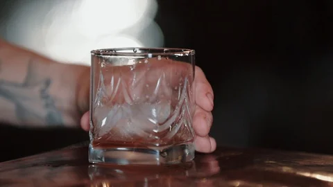 Close-up of ice cubes fall into an empty glass, slow motion. The bartender puts Video stock 129111053