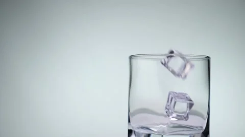Close-up of ice cubes falling into an empty glass. Stock Footage 132489784