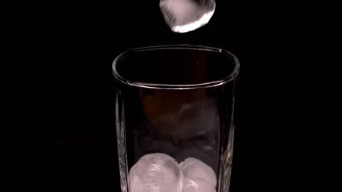 Close-up of ice cubes falling into an empty glass on black background, slow Stock-Footage 150779068