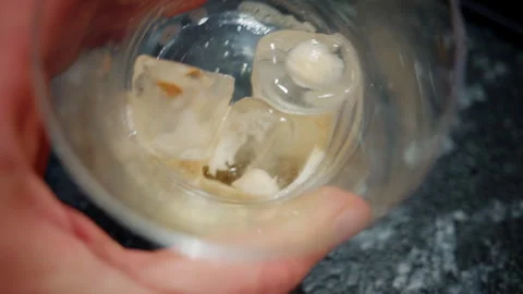 Close up of ice cubes inside a glass held by a person, creating a refreshing Stockbeeldmateriaal 335468782