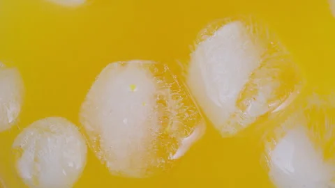 Close up ice cubes in yellow soda, frosty cubes rimmed with sparkling bubbles, b Stock Footage 333942009