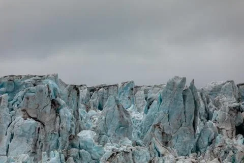Close-up of the ice of a glacier. Blue ice with cloudy sky above. Svalbard Stock Photos