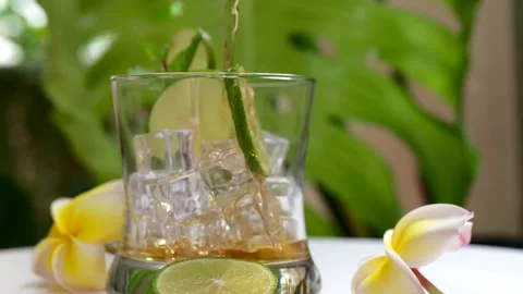 Close up Ice Tea Pouring Into Iced Glass Against Tropical leaf. 스톡 동영상 194525865