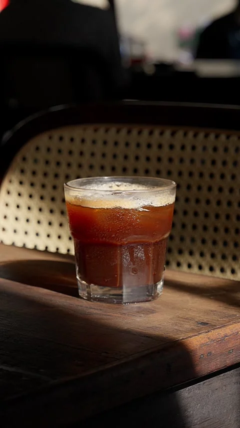 Close up iced brown coffee on an old wooden table in a sunbeam 스톡 동영상 343629605