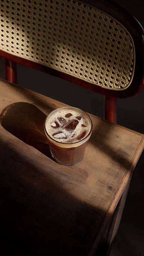 Close up iced brown coffee on an old wooden table in a sunbeam 스톡 동영상 343629618