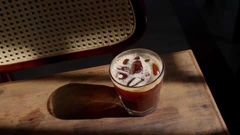 Close up iced brown coffee on an old wooden table in a sunbeam 스톡 동영상 343629694