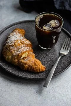 Close-Up of an Iced coffee drink with a fresh vanilla croissant on a table Stock Photos