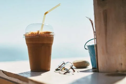 Close-up of iced cold coffee in a plastic cup with a straw and sunglasses o.. Stock Photos